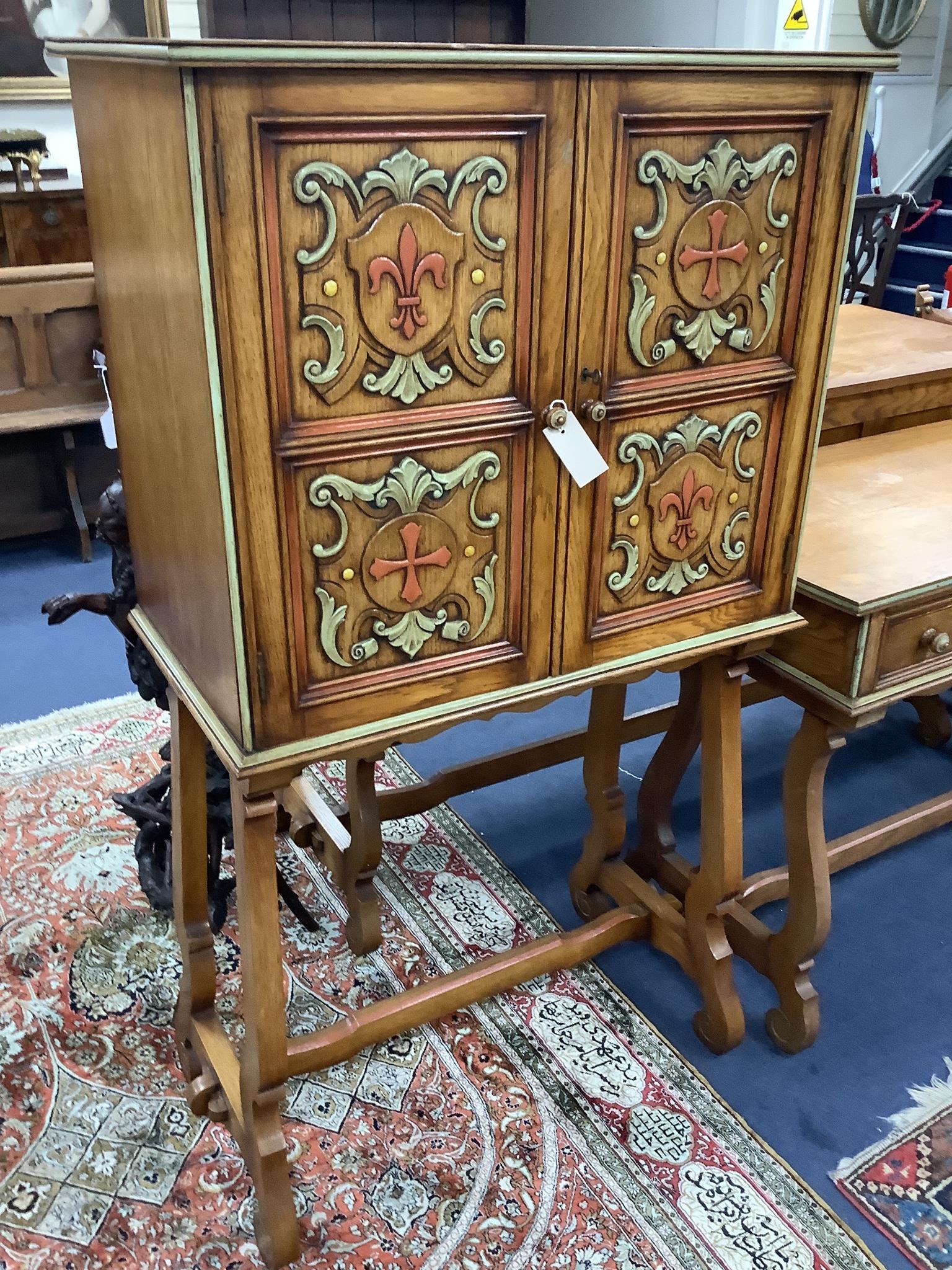 A Maple & Co oak dining suite of Italianate design, with carved and painted decoration and heraldic panels, comprising refectory table, six studded hide-covered chairs, sideboard, two-door cabinet on stand and a side tab